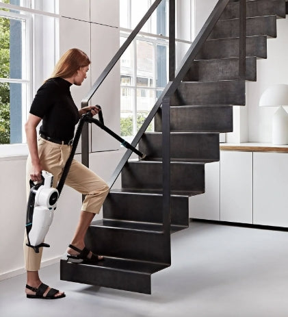 Lifestyle image of person with Lupe Cordless Vacuum going up the stairs